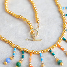 Gold-tone bead necklace with multicolor dangling beads and small charm pendant