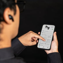 True wireless earbuds near a smartphone screen during setup, with charging case in view