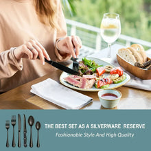 Stainless steel steak knife with black handle beside plated meal