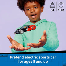 Child holding red and black electric sports car toy with driver in cockpit