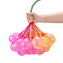 Hand holding a bunch of translucent water balloons in pink, orange, and yellow