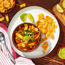 Bowl of bean dip with tortilla chips, jalapeño slices, and lime wedges