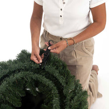 Wreath storage bag strap being fastened around a green wreath