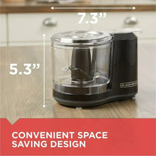 Compact electric food chopper on countertop with clear bowl and black base