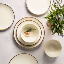 Ceramic dinner plates stacked, off-white centers with thin gold rim
