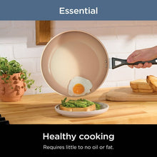 Creamy-beige non-stick saucepan with black handle, frying an egg
