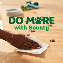 White paper towel sheet held in hand wiping a wooden tabletop