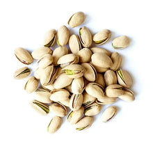 Roasted salted pistachios, pale green kernels and shells scattered on white
