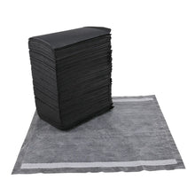 Stack of dark charcoal dog training pads with a gray pad laid on top.