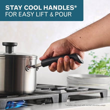 Stainless steel covered saucepan with black handle lifted by hand