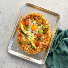 Natural aluminum baking sheet with a topped pizza ready to bake