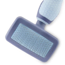 Close-up of dog slicker brush with gray plastic pin pad and blue handle