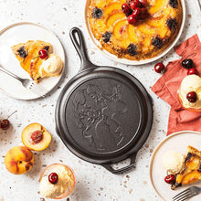 Seasoned cast iron skillet with etched Dolly portrait, shown among plated desserts