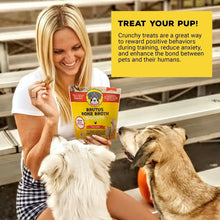 Dog treats bag held by a woman while dogs reach for bone-shaped biscuits