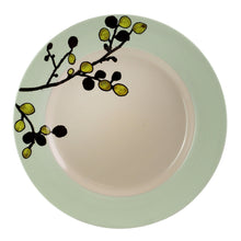Green-rim stoneware dinner plate with floral branch motif across the rim