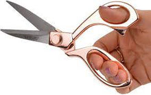 Rose gold metal scissors in hand with closed finger loops and long blades