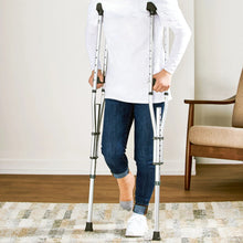 Adult crutches in use with gray underarm pads and hand grips, aluminum legs
