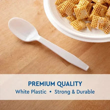 White plastic spoon on plate with crackers, disposable serving utensil