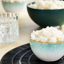 Cooked white rice in a teal bowl on a black tray.