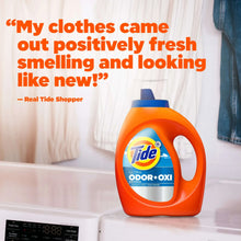 Orange Tide Ultra Odor+Oxi detergent bottle on a white countertop beside folded fabric