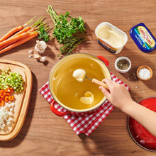 Spreading butter with olive oil and sea salt from a tub onto bread with herbs and veg