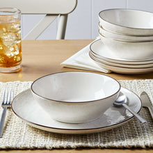 Cream stoneware dinner bowl with speckled finish and dark rim
