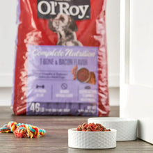 Red dry dog food bag with nutrition panel, plus dog food bowls on a table