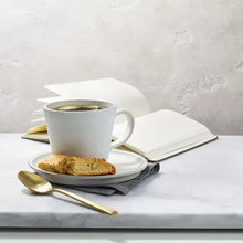 Cup of coffee with slice of cake on saucer and spoon