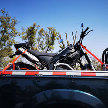 Red motorcycle tie-down straps with metal buckles and black S-hooks on a rack