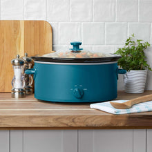 Blue oval slow cooker with glass lid and side handles, stoneware crock visible