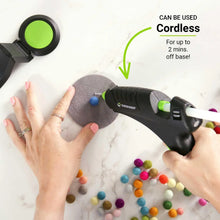 Black and green hot melt glue gun held while applying glue to craft board