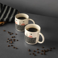Two stoneware cheeky face mugs, cream body with black polka-dot panel and blush details