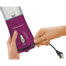 Raspberry personal blender base in hand with power cord plugged in