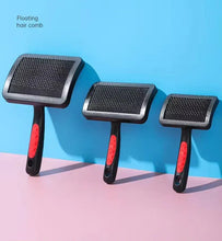 Three slicker brushes with black bristle pads and red handles