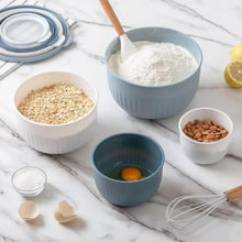 Blue-gray ribbed meal prep bowls with lids, filled with grains, flour, and eggs
