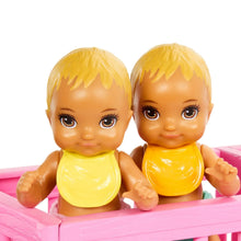 Twin baby dolls in yellow onesies seated in a pink nursery crib