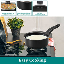 Black saucepan with glass lid and riveted handle, cooking on stovetop
