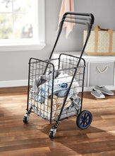 MS shopping cart with wire basket, black frame, blue wheels, filled with folded blankets