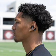 Side view of black open-ear clip earbuds on a person’s ear with ear hook