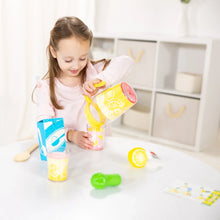 Pretend lemonade play toy pitcher with cups, held by a child at a table
