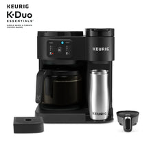 Black coffee maker with stainless carafe, mug, and control panel at top