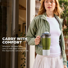 Woman holding a personal blender travel cup with green smoothie, leakproof lid, carry handle.