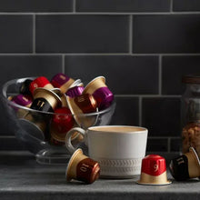 Assorted Nespresso-style coffee pods with espresso cup on countertop