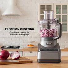 Gray food processor with clear bowl and visible diced onion pieces