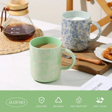 Mint glazed ceramic mug with side handle, with a blue speckled mug beside it