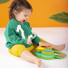 Toddler playing a green musical drum toy with three colorful drum pads and animal artwork