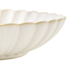 Cream stoneware dinner bowl with scalloped ridged edge, close-up