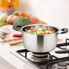 Stainless steel stock pot on gas burner with glass lid and vegetable soup inside