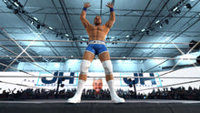 Wrestler in blue trunks and white boots standing in wrestling ring