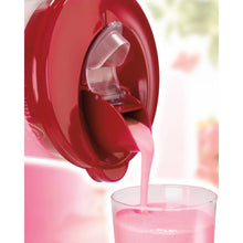 Red blender pour spout dispensing pink smoothie into a cup